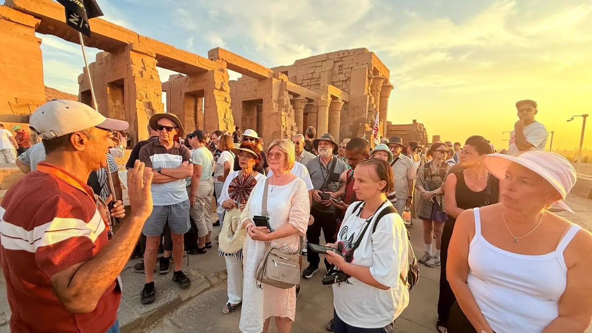 Nourbelle DMC Egyptologist guide holding the company flag while briefing a tour group at Kom Ombo Temple at sunset